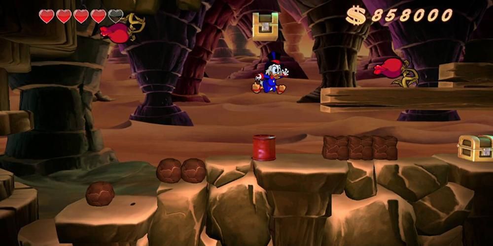 Scrooge McDuck jumping toward a red enemy flower. He's in a large cave with rock pillars behind him