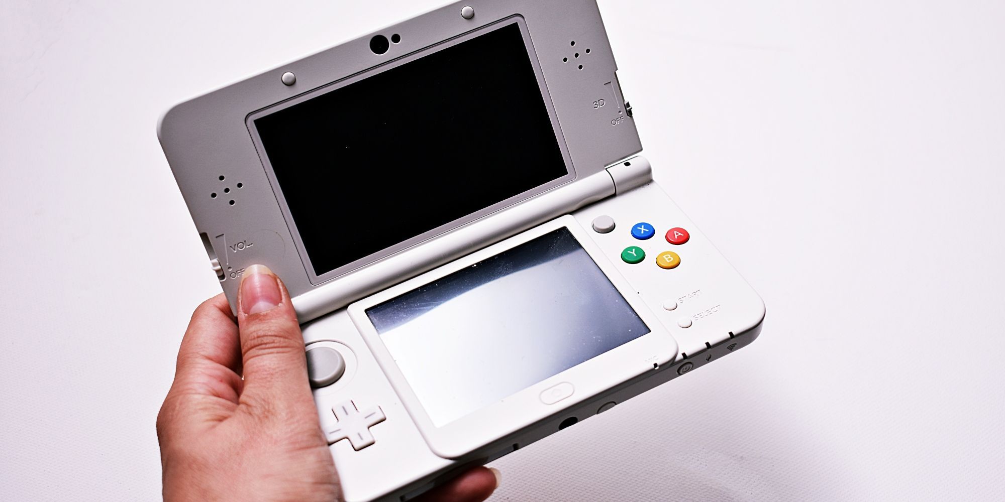 Hand holding up a white New Nintendo 3DS XL console.