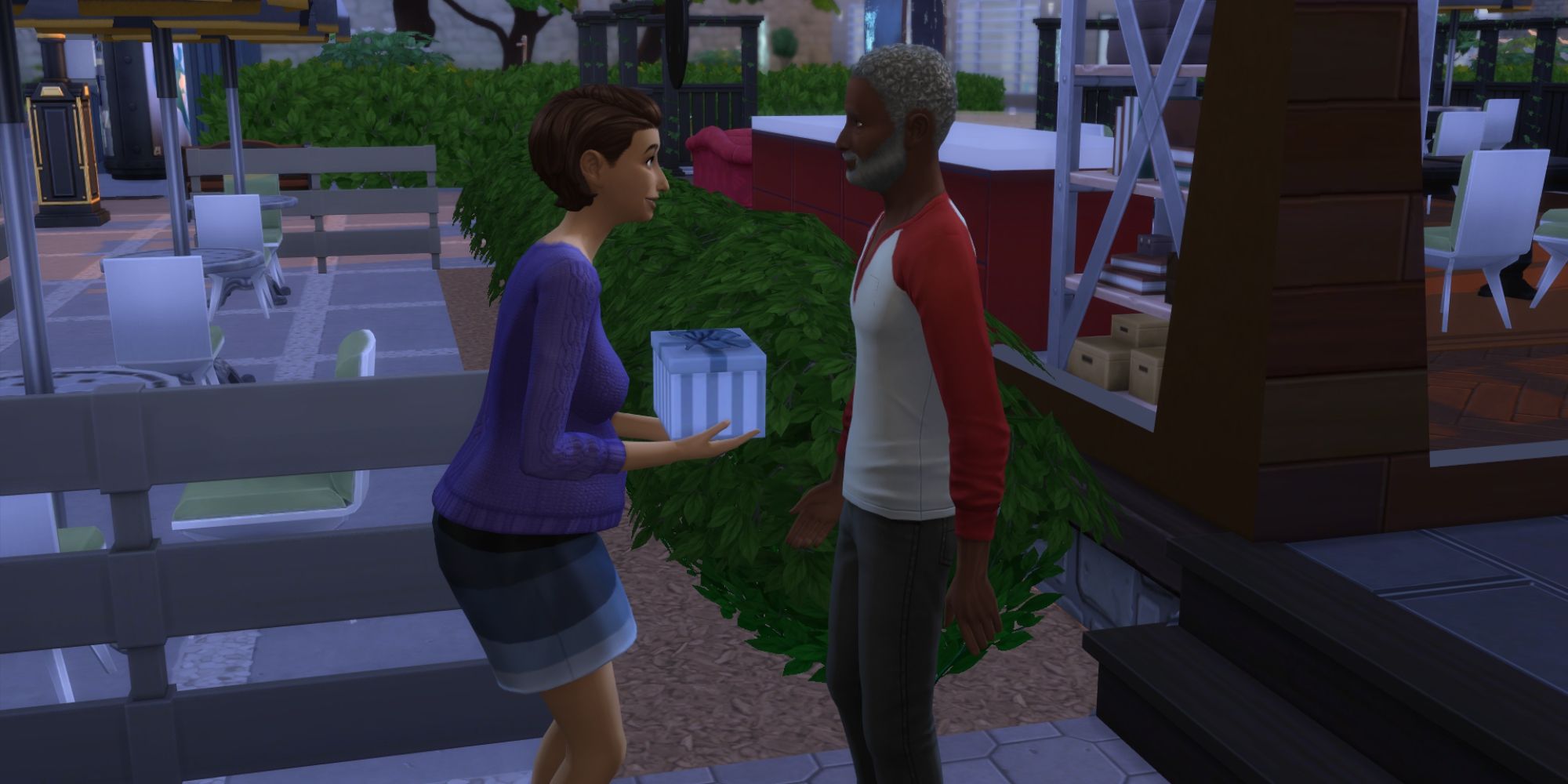 An elderly Sim presents a young pregnant Sim with a gift for her baby shower in the Sims 4.