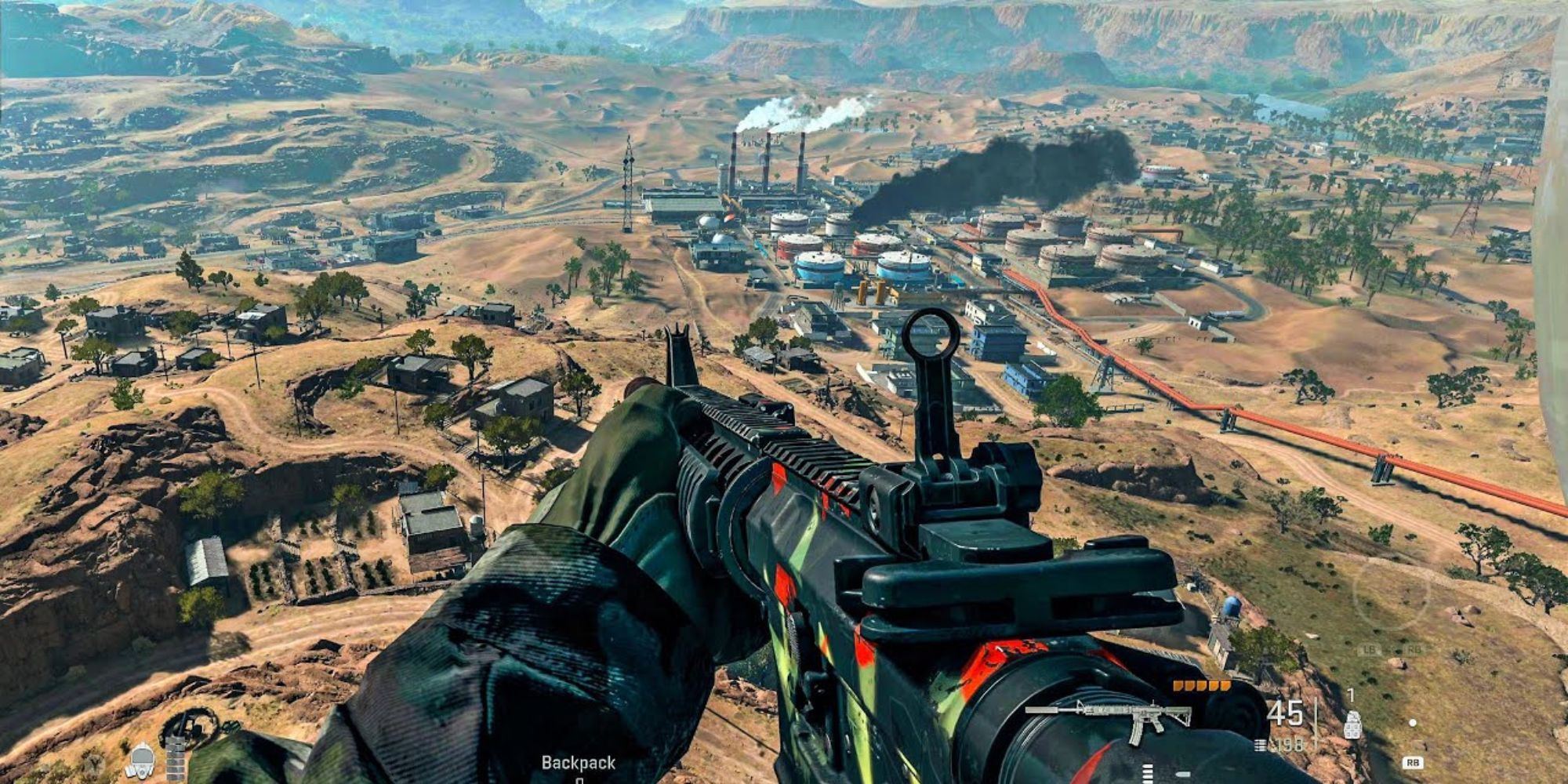 Looking over a large map with a brightly coloured weapon. Lots of smoke coming from buildings and roads can be seen in the game Call Of Duty: Warzone 2.0