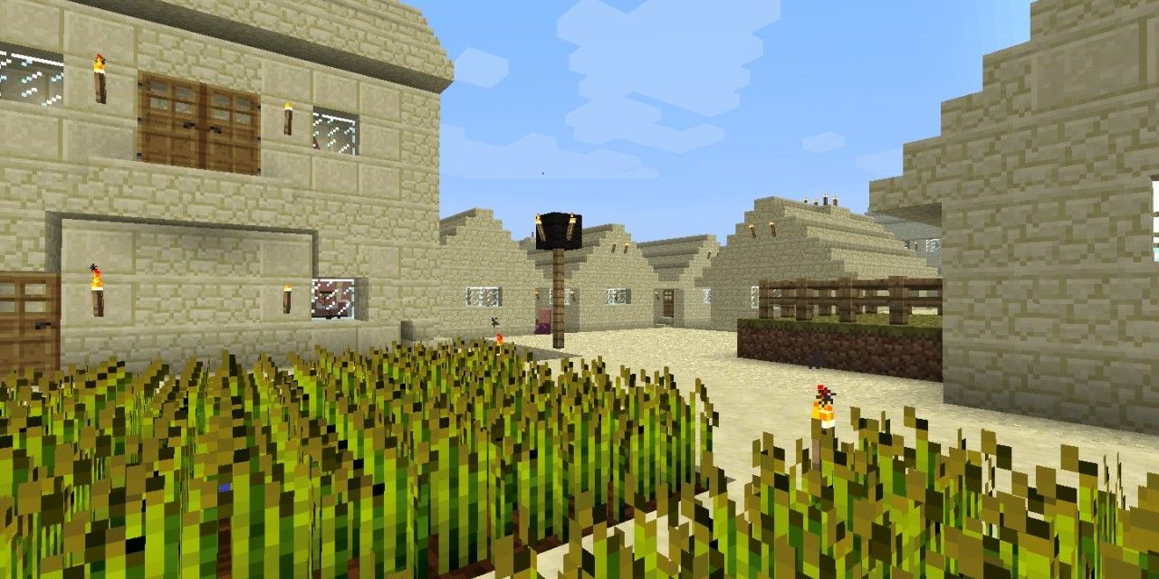 The center of a desert village in Minecraft, showing houses and a wheat field.