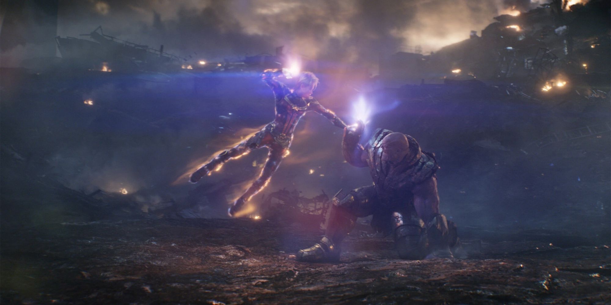 Captain Marvel hovers above Thanos on the battlefield preparing a punch