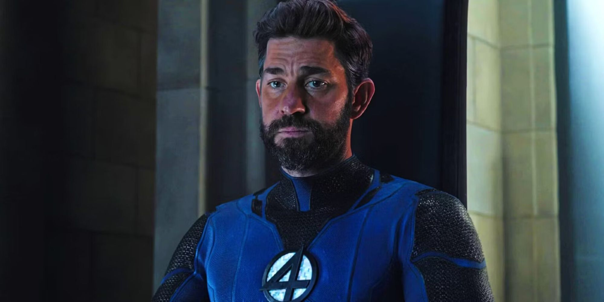 John Krasinski as Reed Richards wearing a blue suit with a four emblem in Doctor Strange in the Multiverse of Madness
