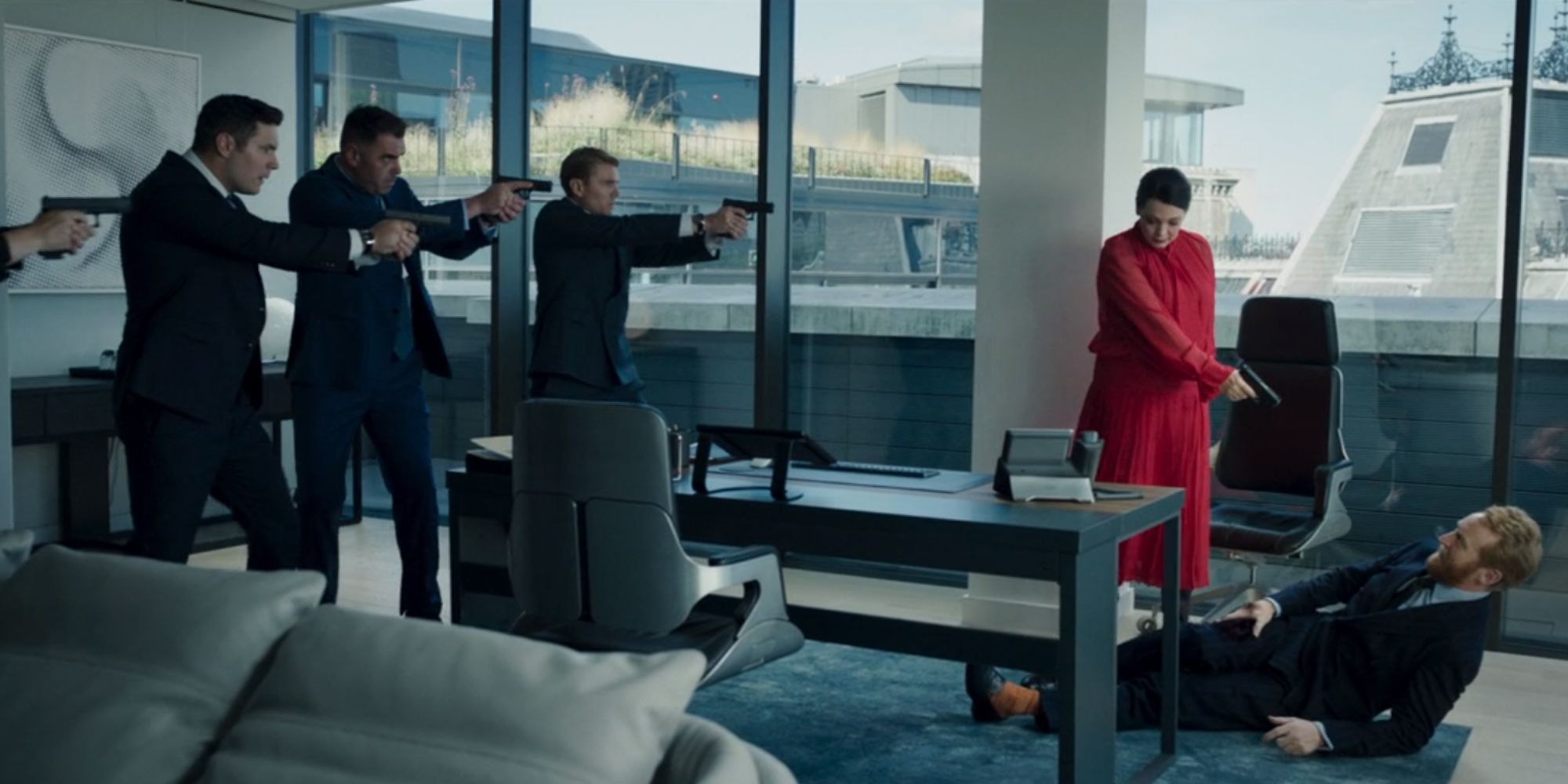 Still from Secret Invasion of Olivia Colman as Sonya Falsworth wearing a red jacket pointing a gun at the director who's lying on the floor while other agents look on