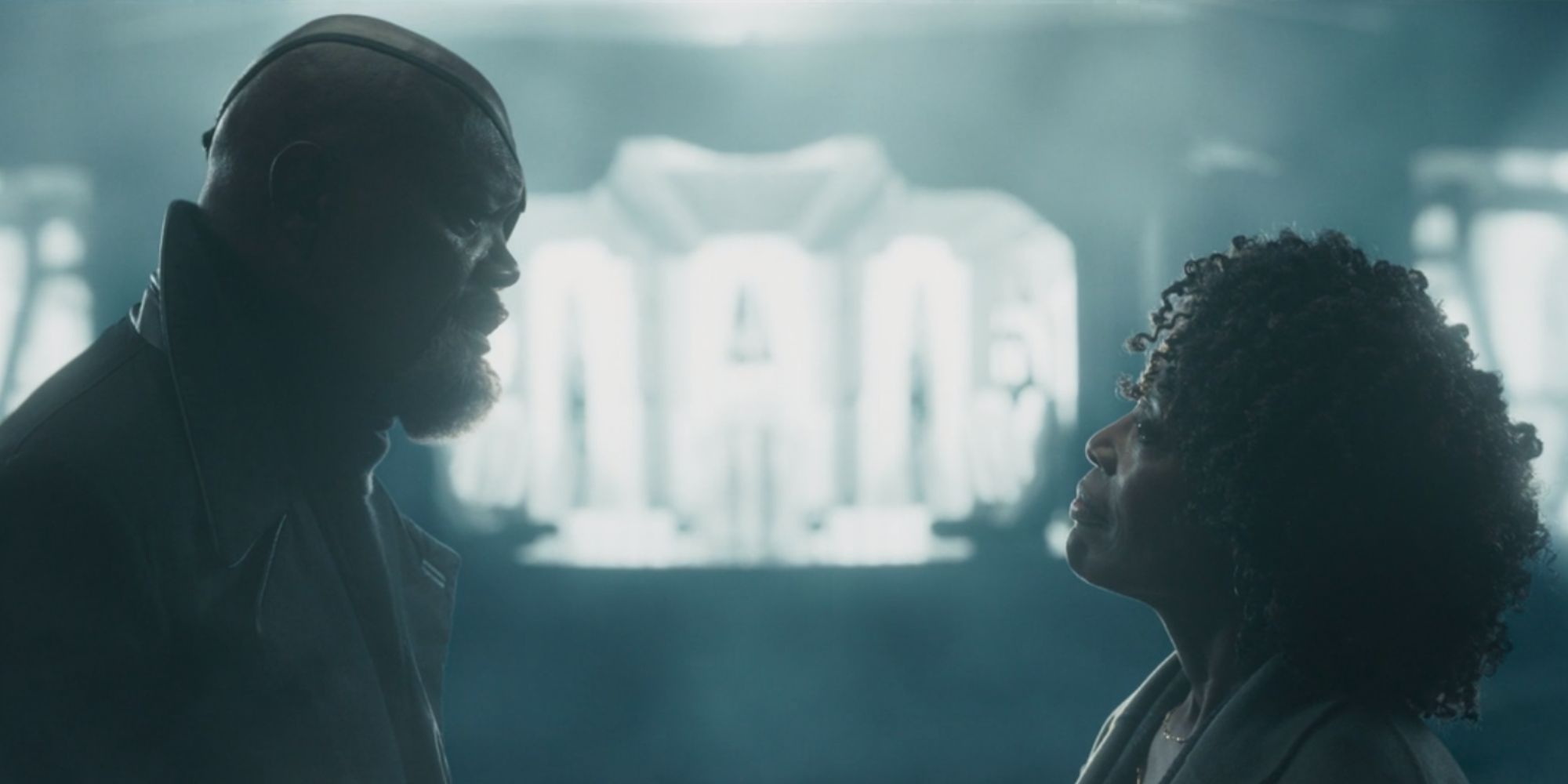 Still of Samuel L. Jackson as Fury and Charlayne Woodard as Priscilla standing opposite each other in front of a beam of light in Secret Invasion