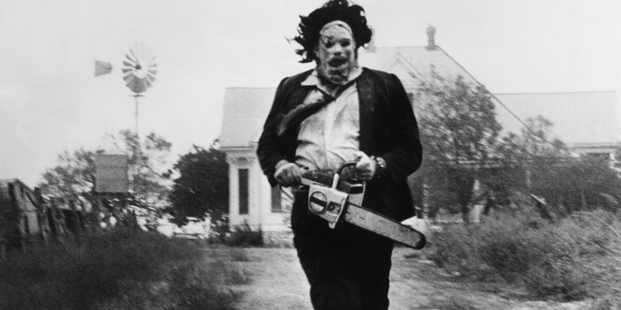 Still of Leatherface in black and white holding a chainsaw in The Texas Chainsaw Massacre