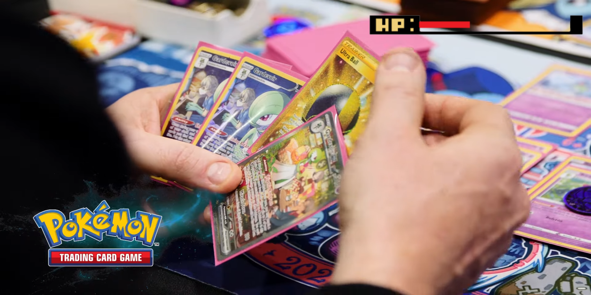 Pokemon TCG player holding 3 gardevoir's and an ultra ball card in front of a play mat, a hp bar is in the top corner displaying low hp