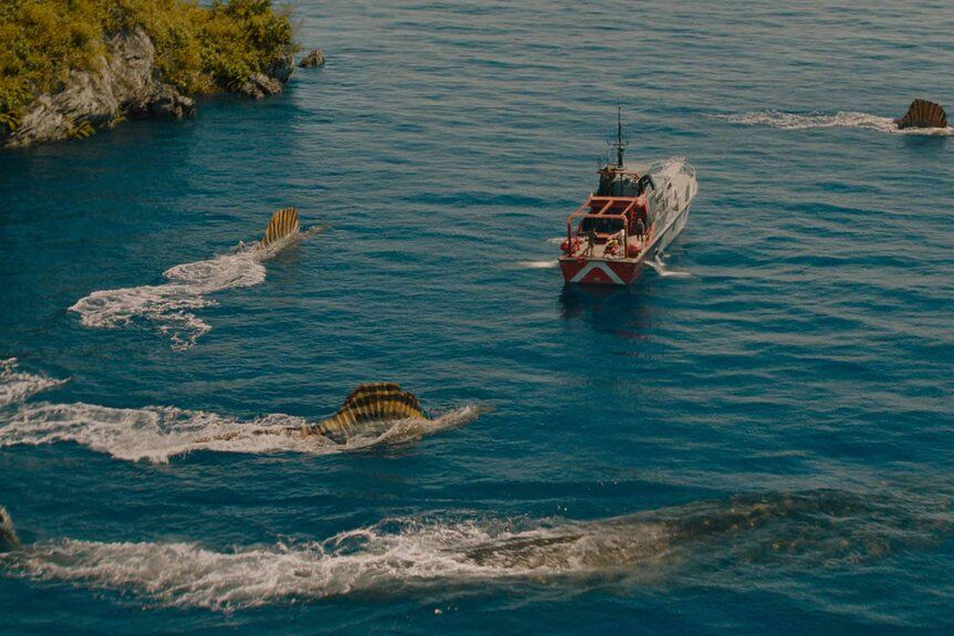 Shot of a trio of Spinosaurus' and a Mosasaurus circling a boat in Jurassic World Rebirth